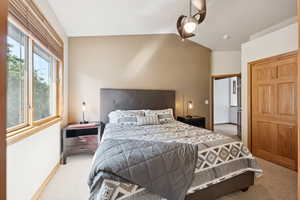 Bedroom with ceiling fan, light carpet, and lofted ceiling