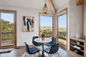 Dining space featuring beam ceiling, healthy amount of natural light, hardwood / wood-style floors, and a chandelier