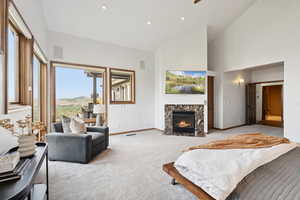 Living room featuring high vaulted ceiling, carpet flooring, and a high end fireplace