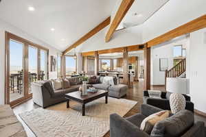 Living room with recessed lighting, wood finished floors, beamed ceiling, stairway, and high vaulted ceiling