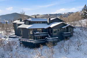 Snow covered rear of property with a chimney and a deck with mountain view
