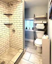 Bathroom featuring a tile shower and light marble finish floors