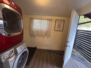 Washroom featuring dark wood-style flooring and stacked washer / dryer