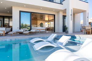 View of swimming pool with a patio, a pool with connected hot tub, and a balcony
