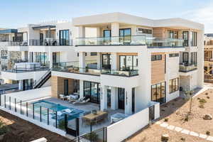 Rear view of house with stucco siding, a patio, a community pool, and a balcony