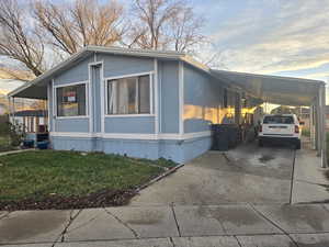 Property exterior at dusk with driveway, an attached carport, and a lawn