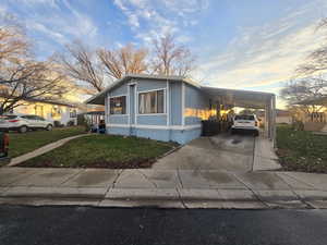 Manufactured / mobile home with a lawn, a carport, and driveway
