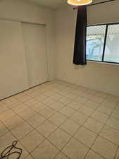 Unfurnished bedroom featuring a closet and light tile patterned floors