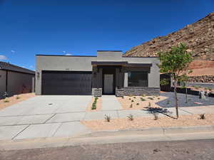 Contemporary home with stucco siding, concrete driveway, a garage, and stone siding