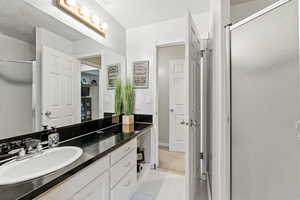 Full bathroom with vanity, a stall shower, a textured ceiling, and light tile patterned floors