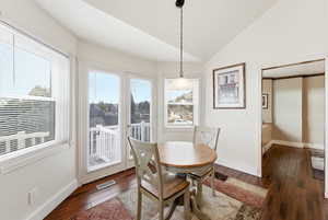 Dining area with vaulted ceiling, dark wood-style flooring, and a textured ceiling
