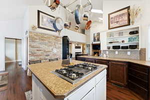 Kitchen with white cabinetry, a center island, a lit fireplace, stainless steel gas cooktop, and dark wood-style flooring
