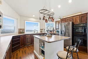 Kitchen featuring open shelves, a kitchen island, stainless steel fridge with ice dispenser, dark wood-type flooring, and light countertops
