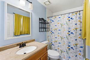 Full bathroom with vanity and a textured ceiling