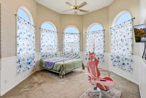 Carpeted bedroom featuring wainscoting and ceiling fan