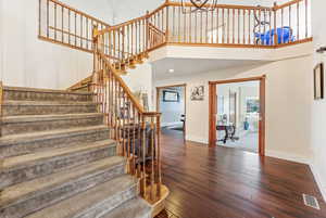 Staircase featuring a high ceiling, wood-type flooring, and recessed lighting