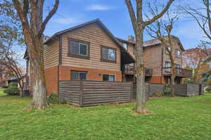 Back of property with a lawn, brick siding, and a balcony