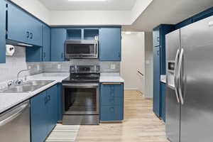 Kitchen featuring blue cabinets, appliances with stainless steel finishes, and open shelves