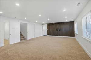 Below grade area featuring stairway, light colored carpet, wood walls, recessed lighting, and an accent wall
