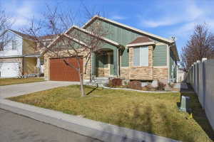 View of front of home with stone siding, concrete driveway, and an attached garage
