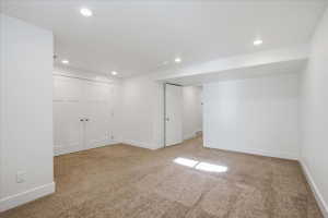 Below grade area with light colored carpet and recessed lighting