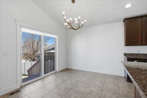 Unfurnished dining area featuring vaulted ceiling, a chandelier, and light tile patterned floors