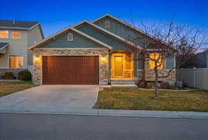Craftsman-style home featuring stone siding, driveway, and a garage