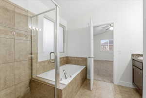 Bathroom featuring vaulted ceiling, a bath, a stall shower, vanity, and light tile patterned floors