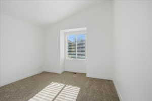 Unfurnished room with light carpet and lofted ceiling