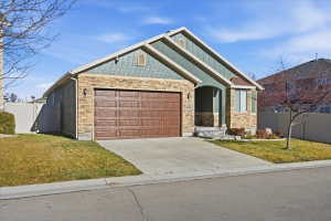 Craftsman house with stone siding, driveway, and an attached garage