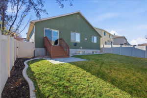 Rear view of house featuring a fenced backyard, a patio area, stucco siding, and a gate