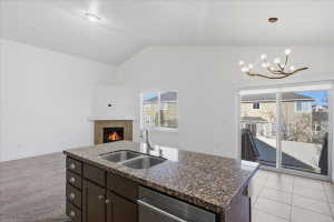 Kitchen with a center island with sink, dark brown cabinets, a tiled fireplace, open floor plan, and dishwasher
