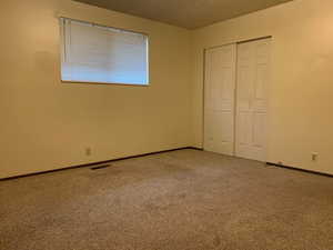 Unfurnished bedroom with carpet floors, a closet, and a textured ceiling