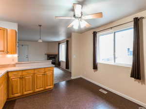 Kitchen featuring dark floors, pendant lighting, a glass covered fireplace, and light countertops