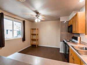 Kitchen with black appliances, light aggregate flooring, a ceiling fan, and light countertops