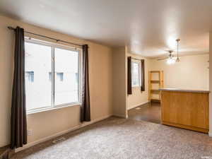 Unfurnished living room featuring dark carpet and ceiling fan