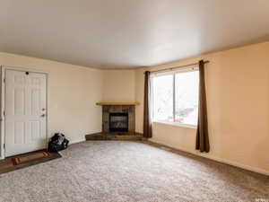 Unfurnished living room featuring a fireplace and carpet flooring