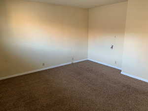 Empty room with baseboards and dark colored carpet