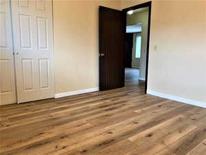 Unfurnished bedroom featuring wood finished floors and a closet