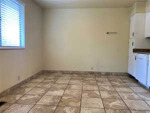 Unfurnished dining area with light tile patterned flooring and baseboards