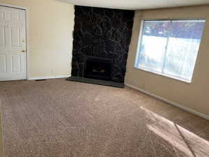 Unfurnished living room with carpet, a fireplace, and a textured ceiling