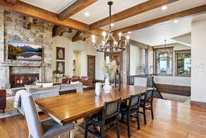 Dining space featuring a chandelier, a stone fireplace, and light wood-style floors