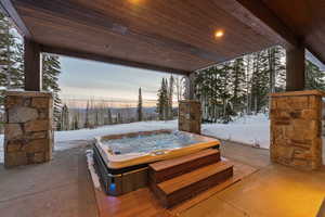Patio terrace at dusk featuring a hot tub and a patio area