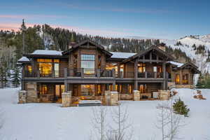 Snow covered property with a chimney and stone siding
