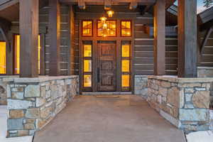 View of exterior entry with stone siding and covered porch