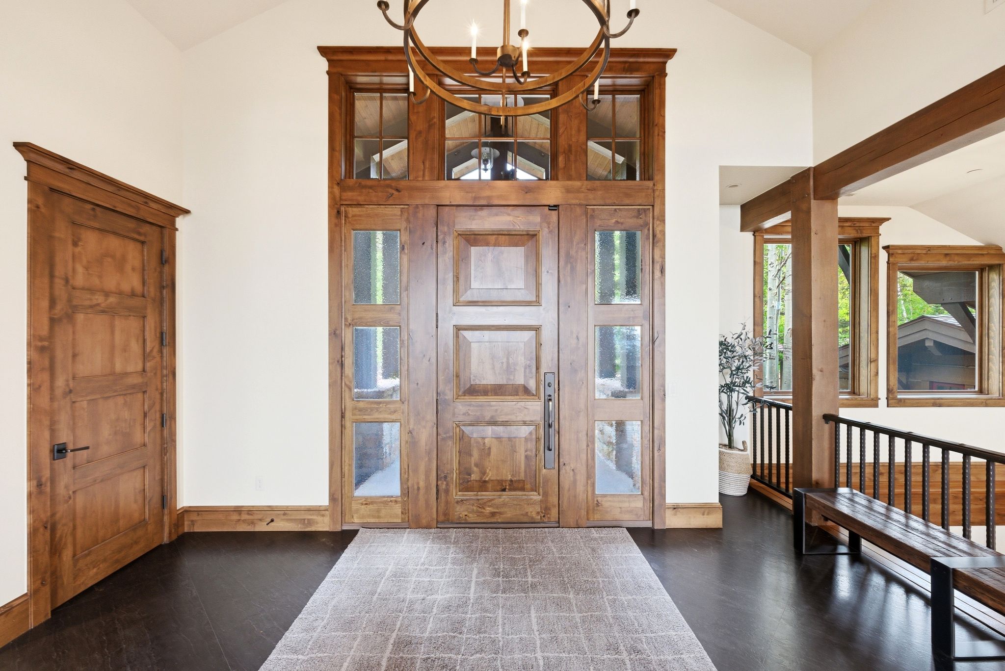 Grand entryway featuring a paneled wood door with sidelights, transom windows, and a vaulted ceiling
