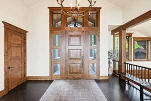 Grand entryway featuring a paneled wood door with sidelights, transom windows, and a vaulted ceiling
