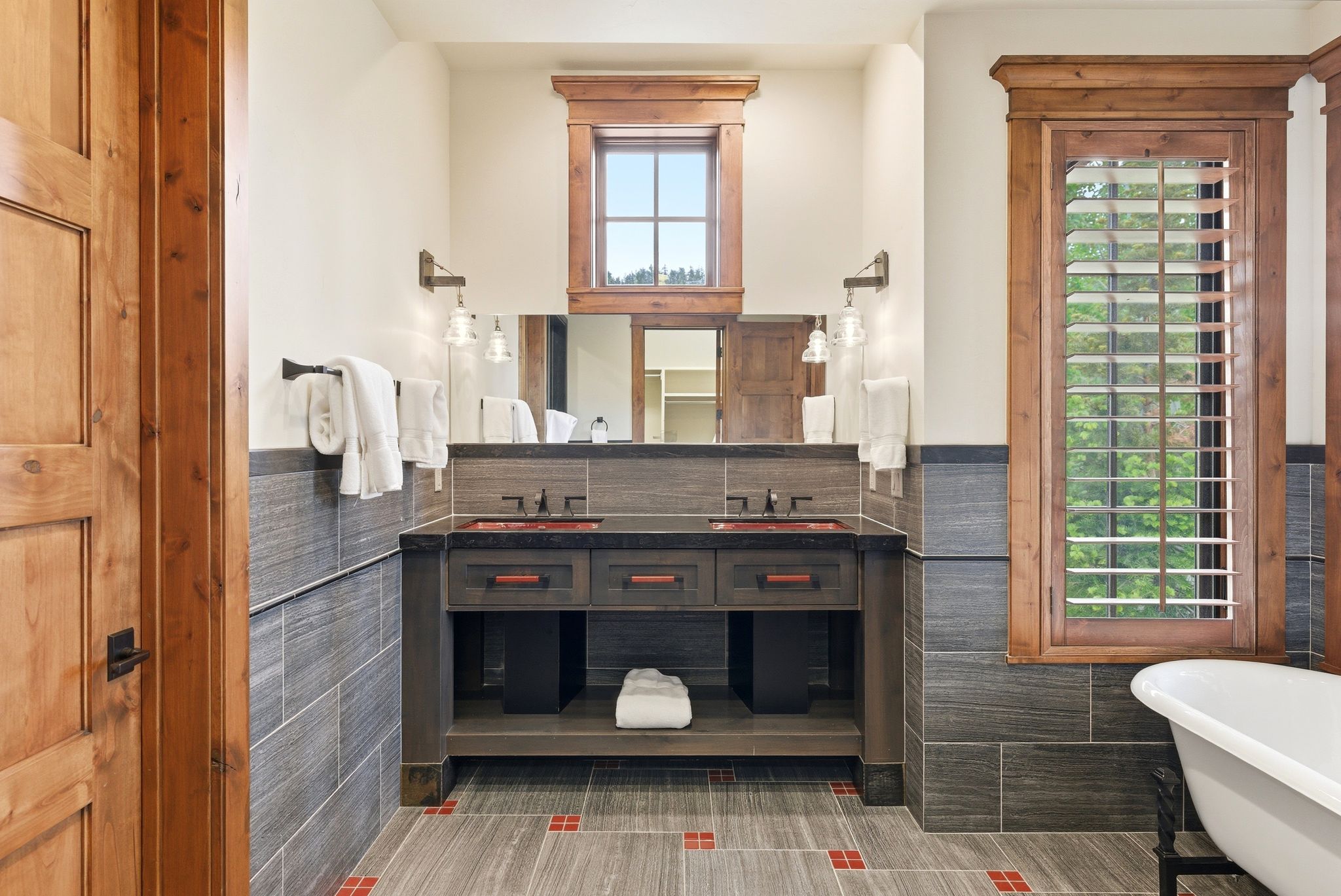 Bathroom featuring a dual vanity with vessel sinks, integrated mirrors, and wall-mounted sconces