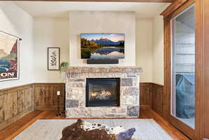 Living room featuring a wainscoted wall, a fireplace, hardwood / wood-style flooring, and wooden walls