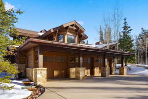 View of front of property with a porch, stone siding, a garage, and concrete driveway